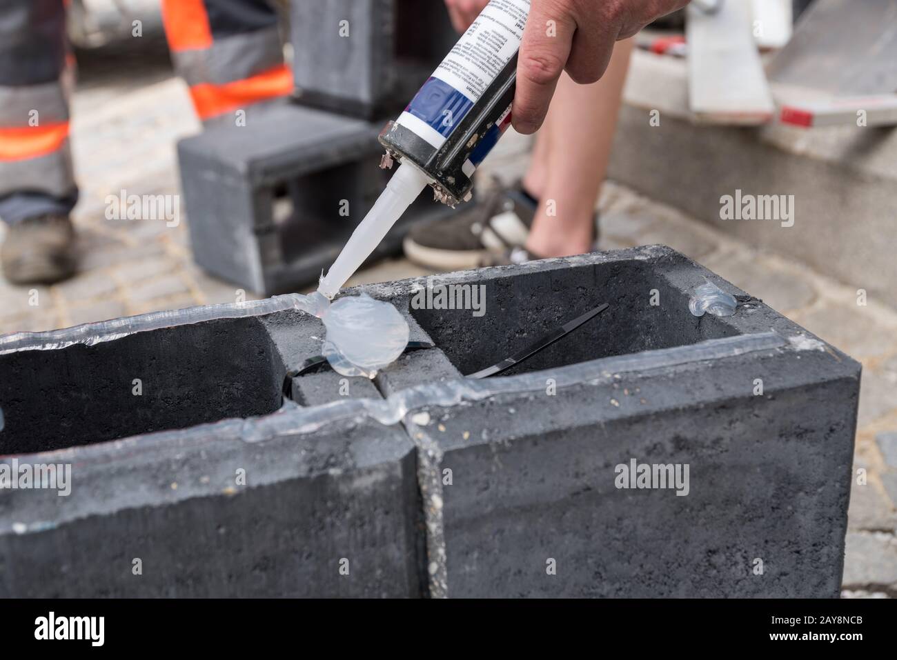 Bricklayers working with silicone and concrete bricks - close-up Stock Photo