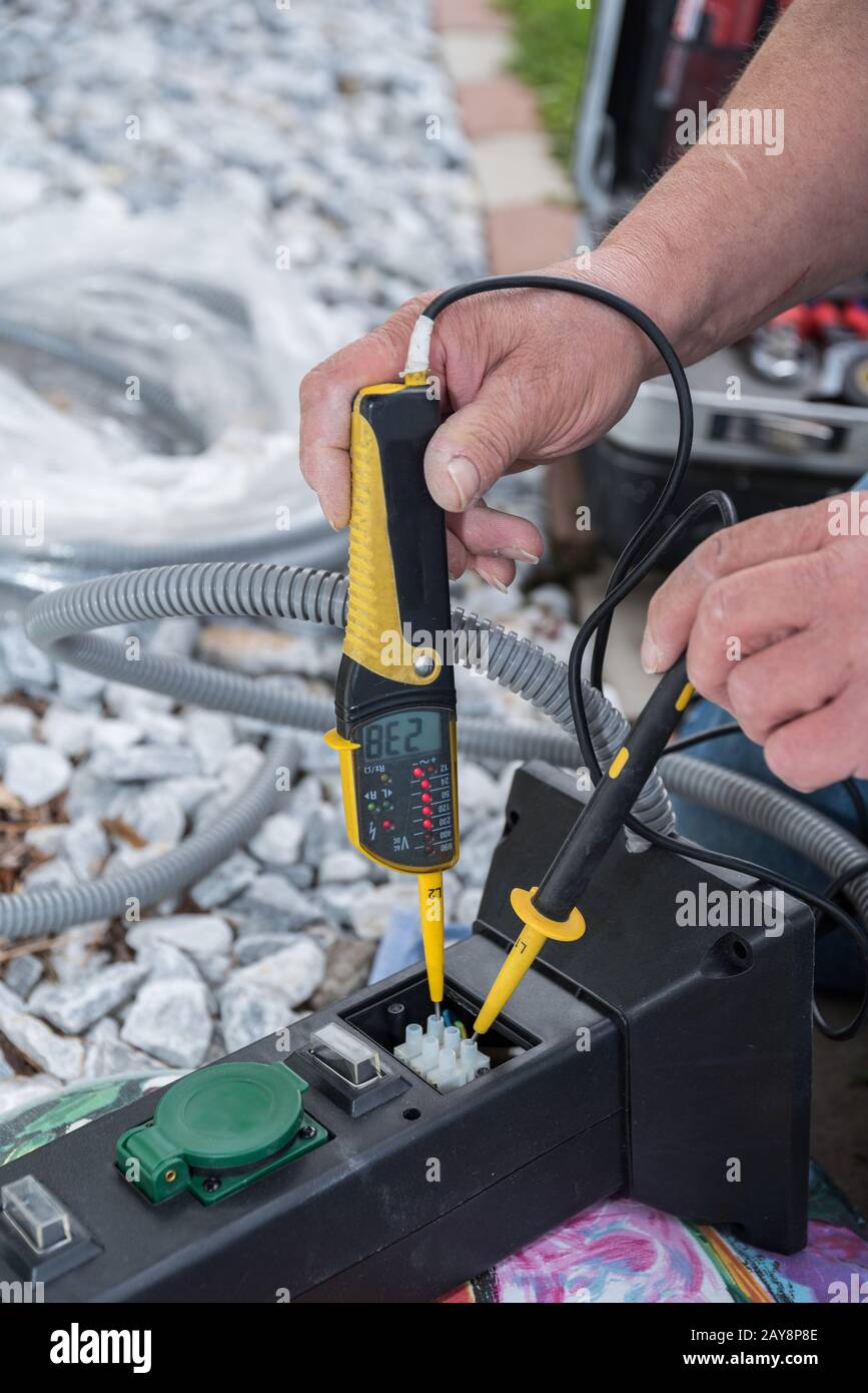 Electrician checks socket voltage with voltage tester Stock Photo