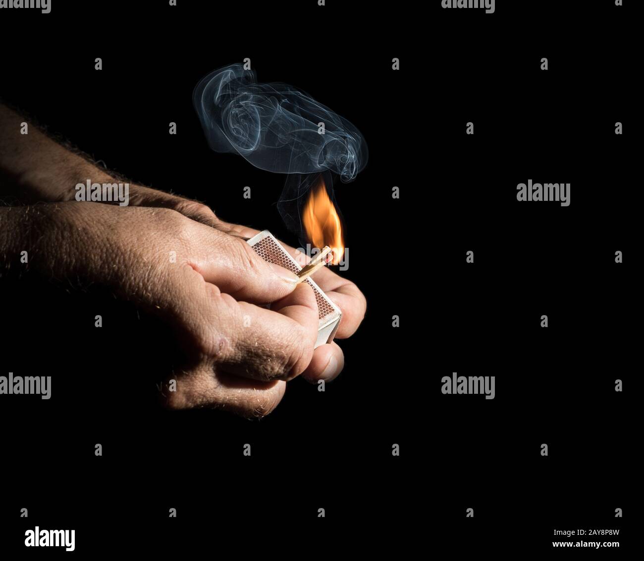 Two hands light a stick wood with a small cloud of smoke Stock Photo