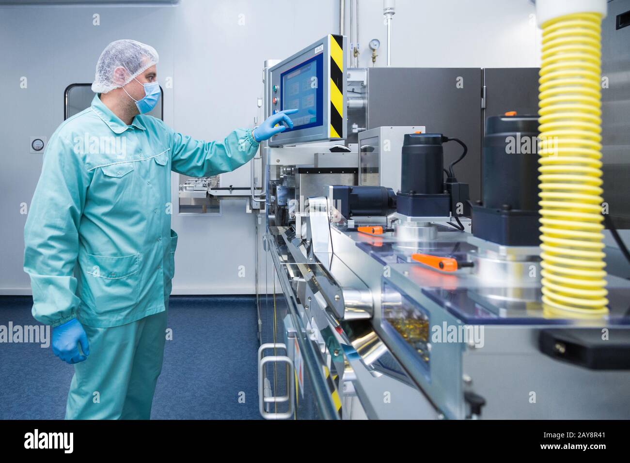 Pharmacy industry factory man worker in protective clothing in sterile working conditions operating on pharmaceutical equipment Stock Photo