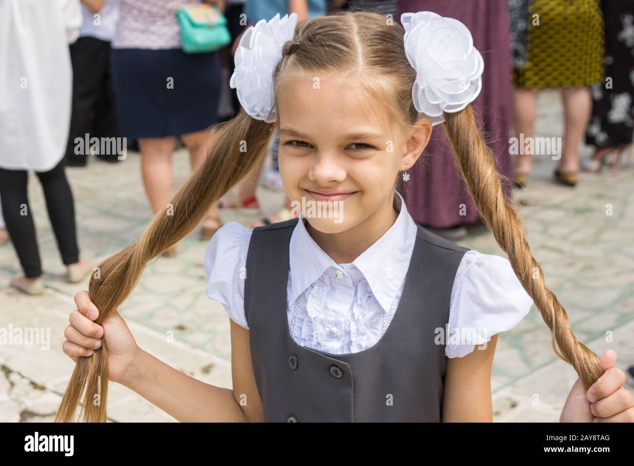 Schoolgirl at the festival on September 1 holds her long hair in her hands Stock Photo