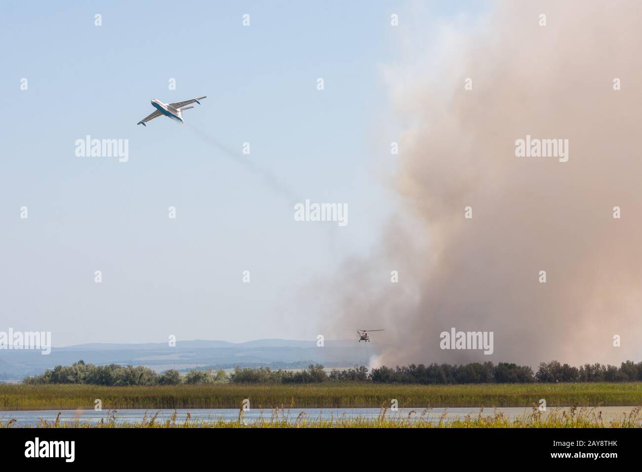 Extinguishing fire from the air using an airplane and a helicopter, with the burning of reeds on the floodplains of the Anapka R Stock Photo