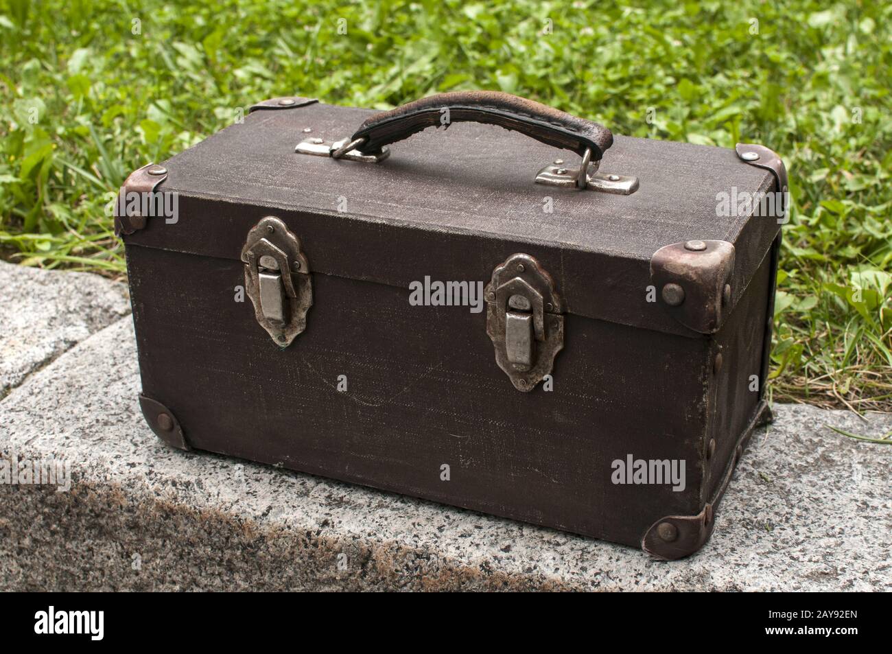 Old used weathered vintage grunge suitcase on stone pavement closeup in house backyard Stock Photo