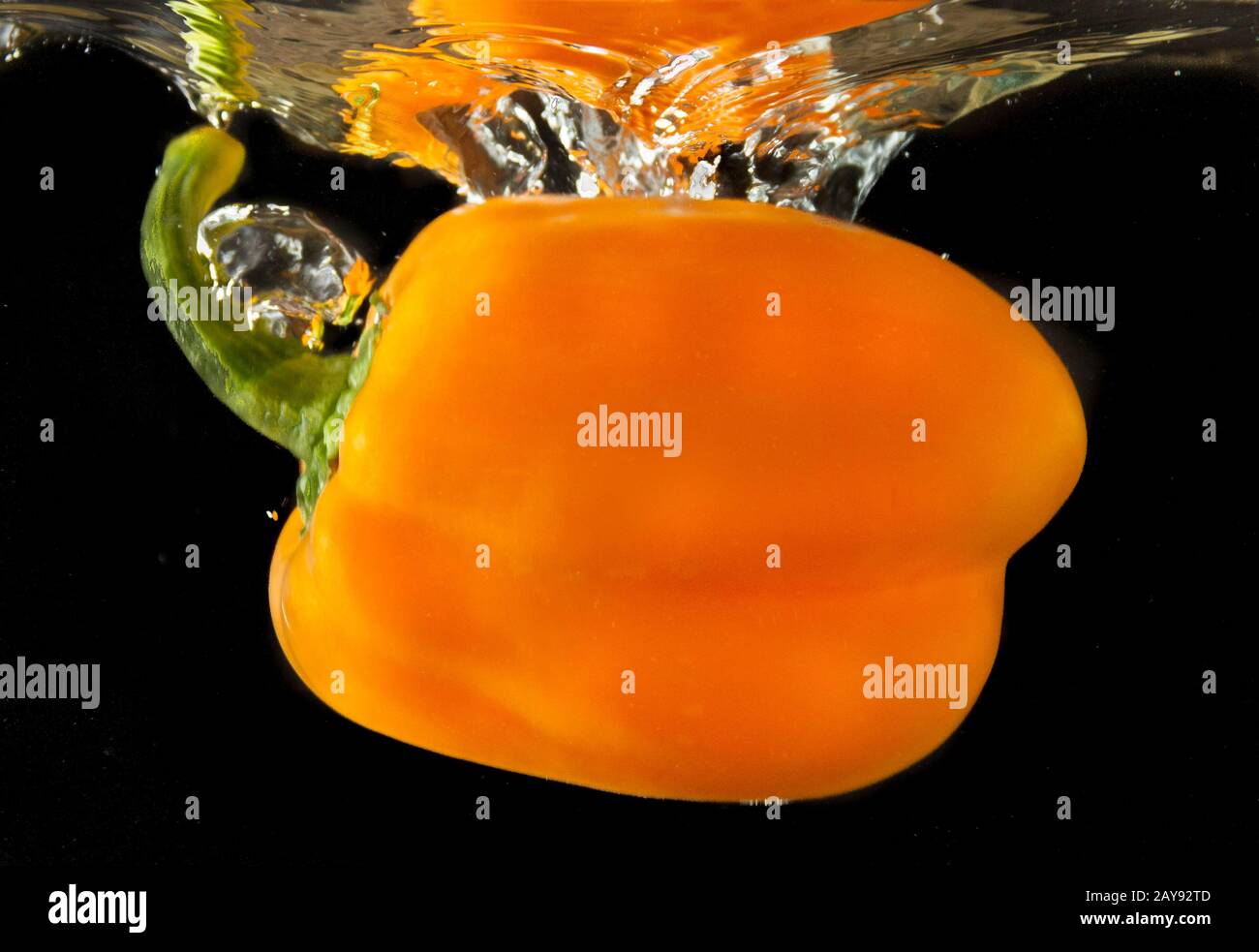 Colorful orange sweet bell pepper dropping in a water tank Stock Photo