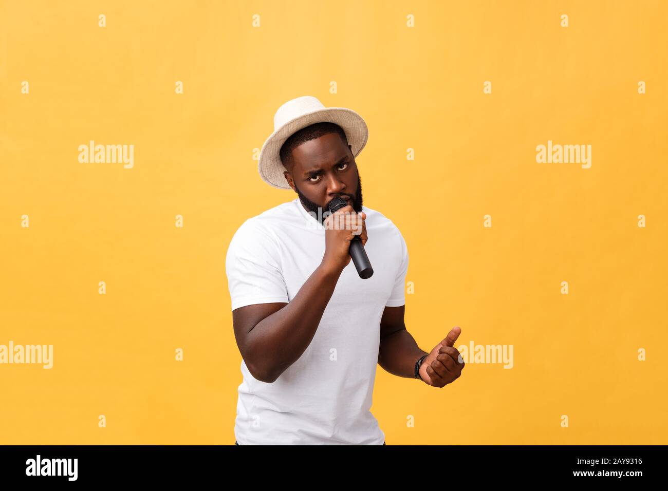 young handsome african american boy singing emotional with microphone isolated on yellow background, in motion gesturing Stock Photo