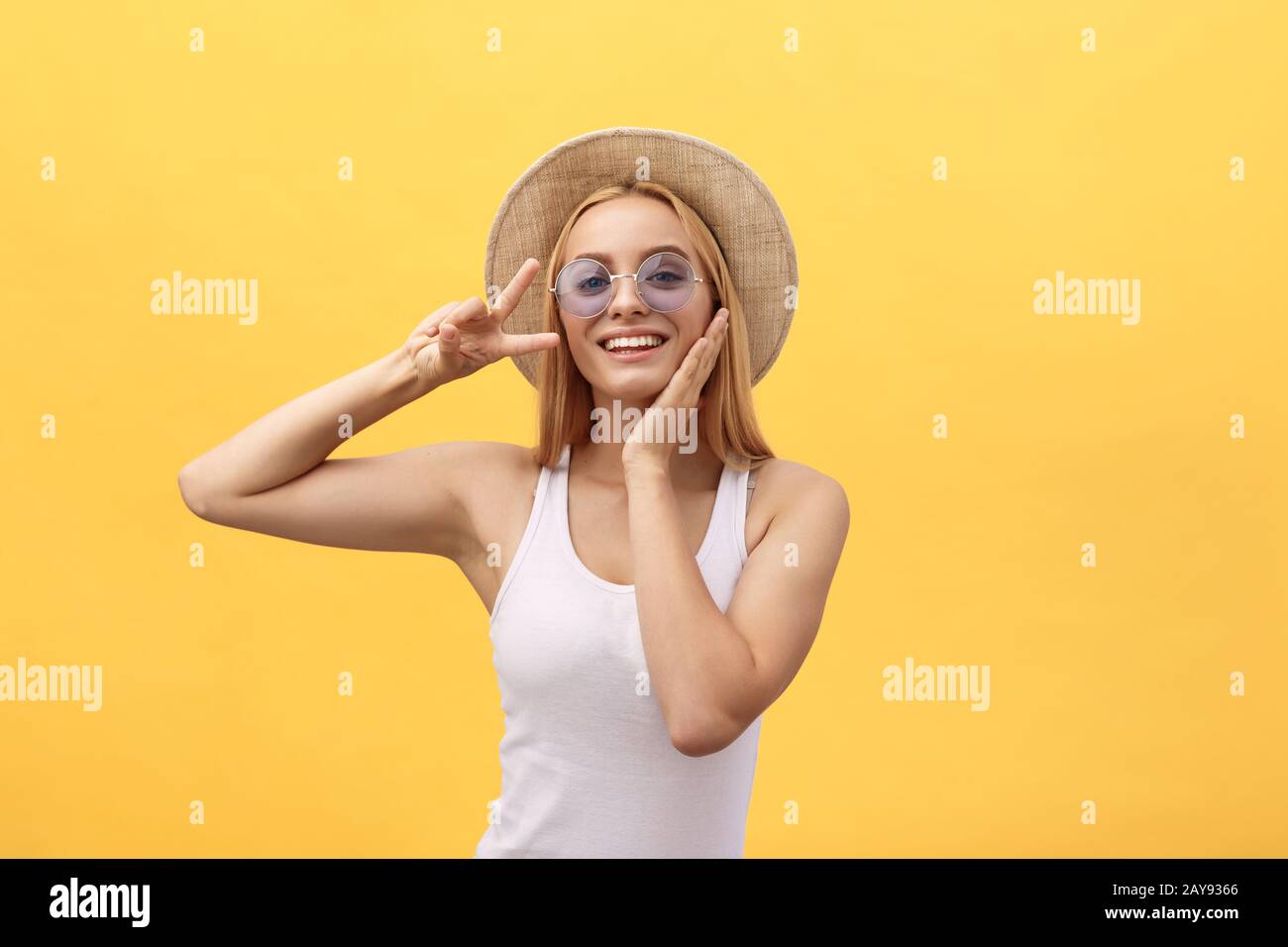 Image of cheerful caucasian woman wearing casual clothing smiling and showing peace sign with two fingers isolated over yellow b Stock Photo