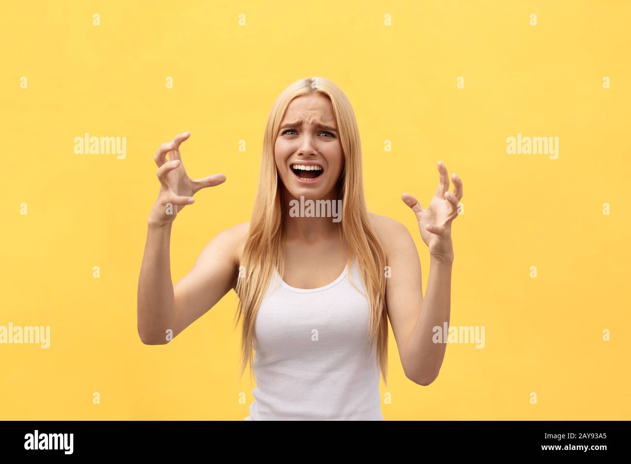 Portrait of a happy excited woman in white shirt with open mouth isolated over yellow background Stock Photo