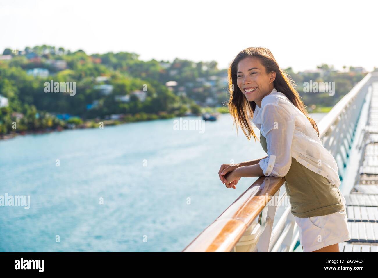 Cruise ship vacation Asian woman relaxing on deck enjoying view from boat of port of call city on St. Lucia island in the Caribbean. Happy casual tourist girl outside on tropical holiday destination. Stock Photo