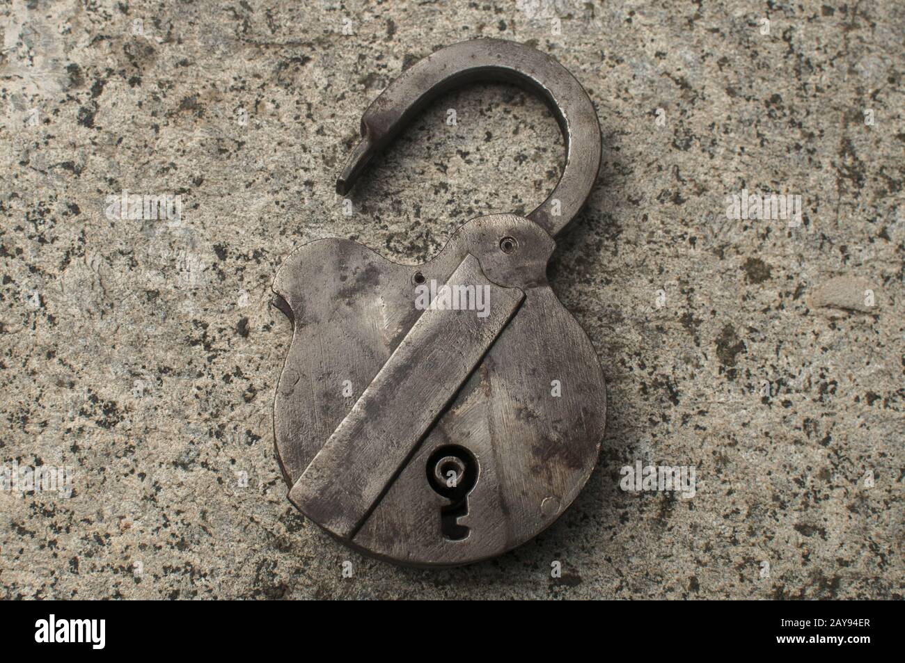 Old weathered grunge retro open padlock closeup on solid stone surface background Stock Photo