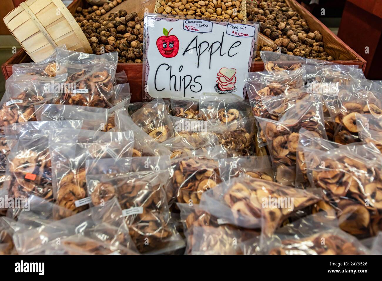 Pack of hand made apple chips, with or without cinnamon, at the local market. Chips packed in plastic bags. Hand written price sign. Organic food. Stock Photo