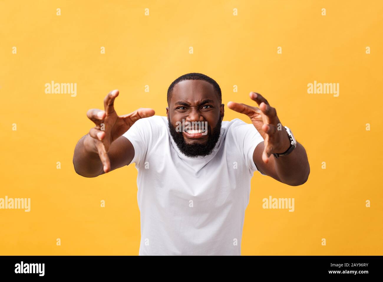 Portrait of african american man with hands raised in shock and disbelief. Isolated over yellow background. Stock Photo