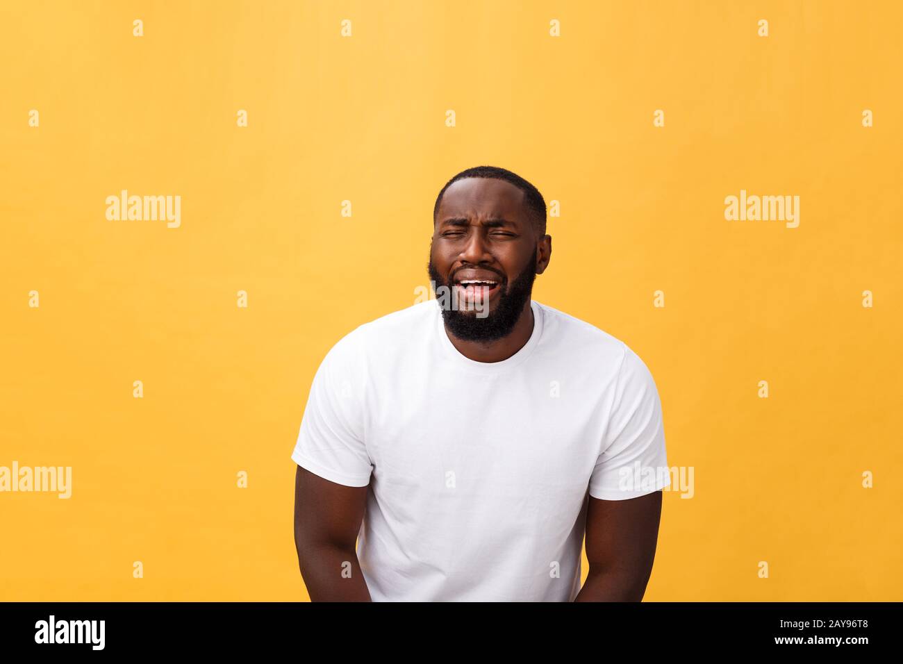 Young Stressed man with face showing sadness and despair. Isolated over yellow background. Stock Photo