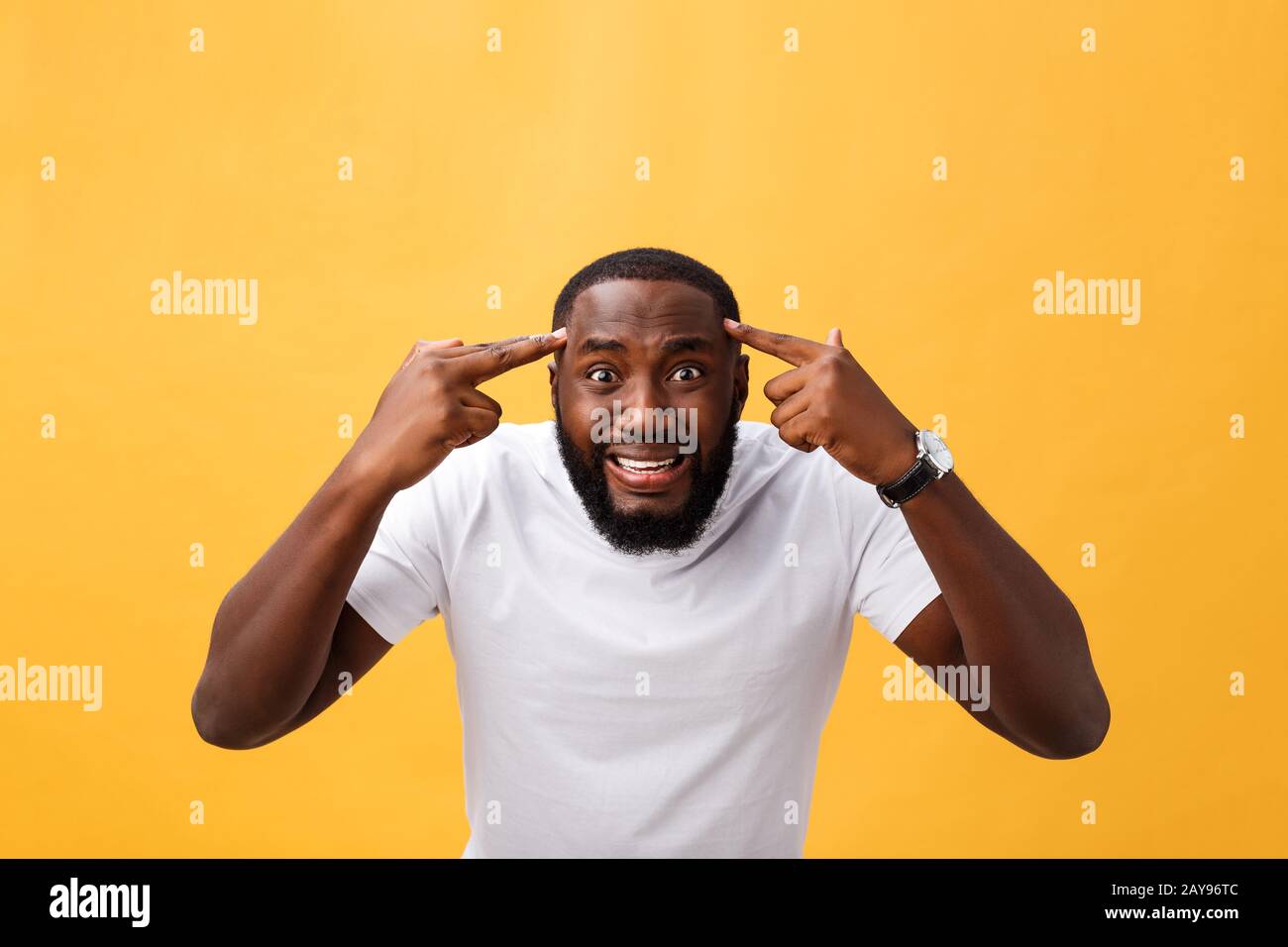 Portrait of african american man with hands raised in shock and disbelief. Isolated over yellow background. Stock Photo