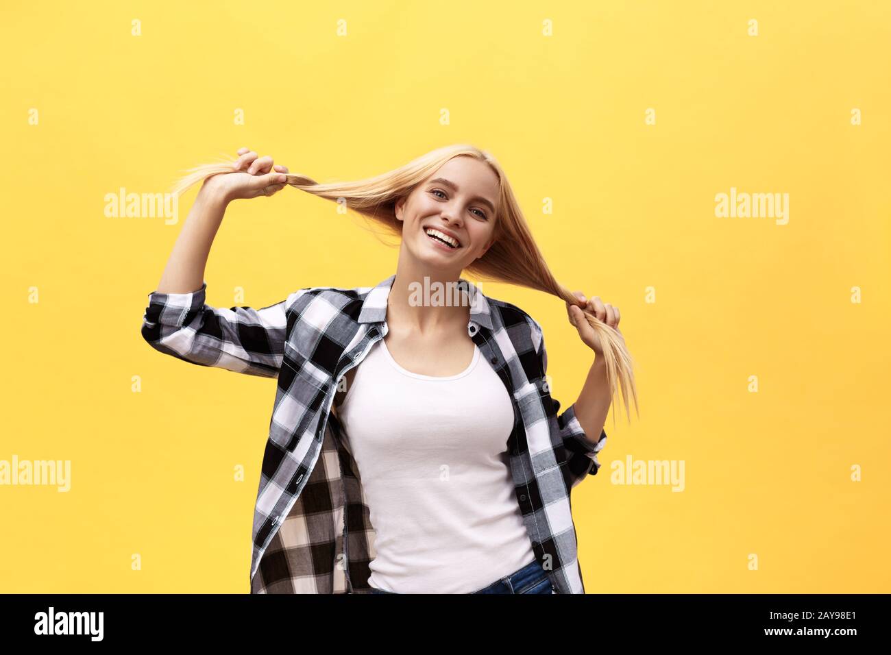 Beautiful pretty charming young blonde woman smiling happily, having fun indoors, playing with long straight hair. Pretty girl l Stock Photo