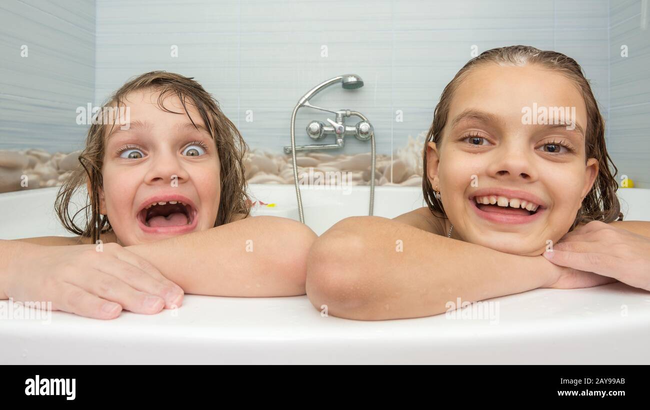 Two sisters bathe in the bath and make fun faces Stock Photo