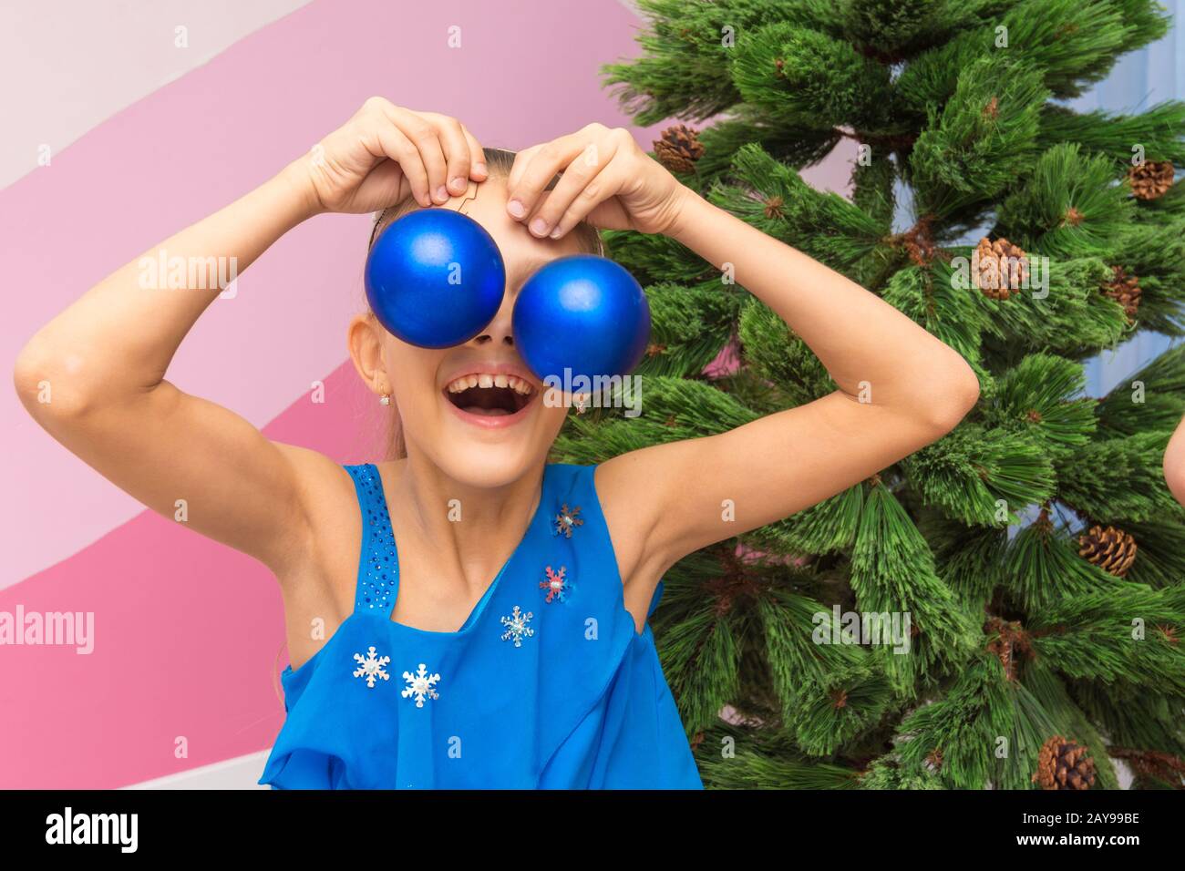 The girl put big Christmas balls to her eyes Stock Photo
