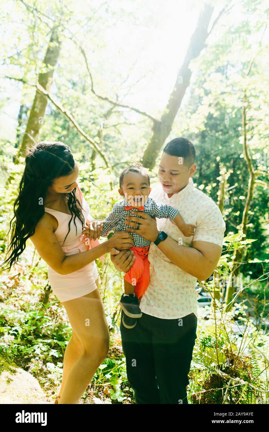 A family of three with a baby boy stand together on a summer day Stock Photo