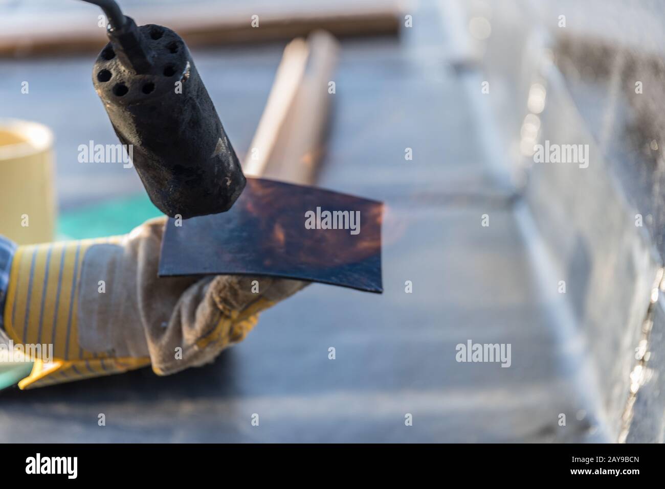Construction worker at construction site with gas blaze seals with BItumen weld on roof - close-up f Stock Photo