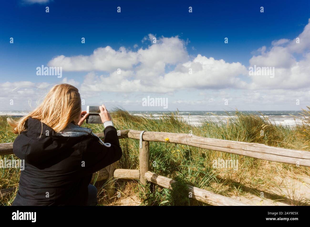 Woman is taking a snapshot of the beach the sea and the dunes Stock Photo