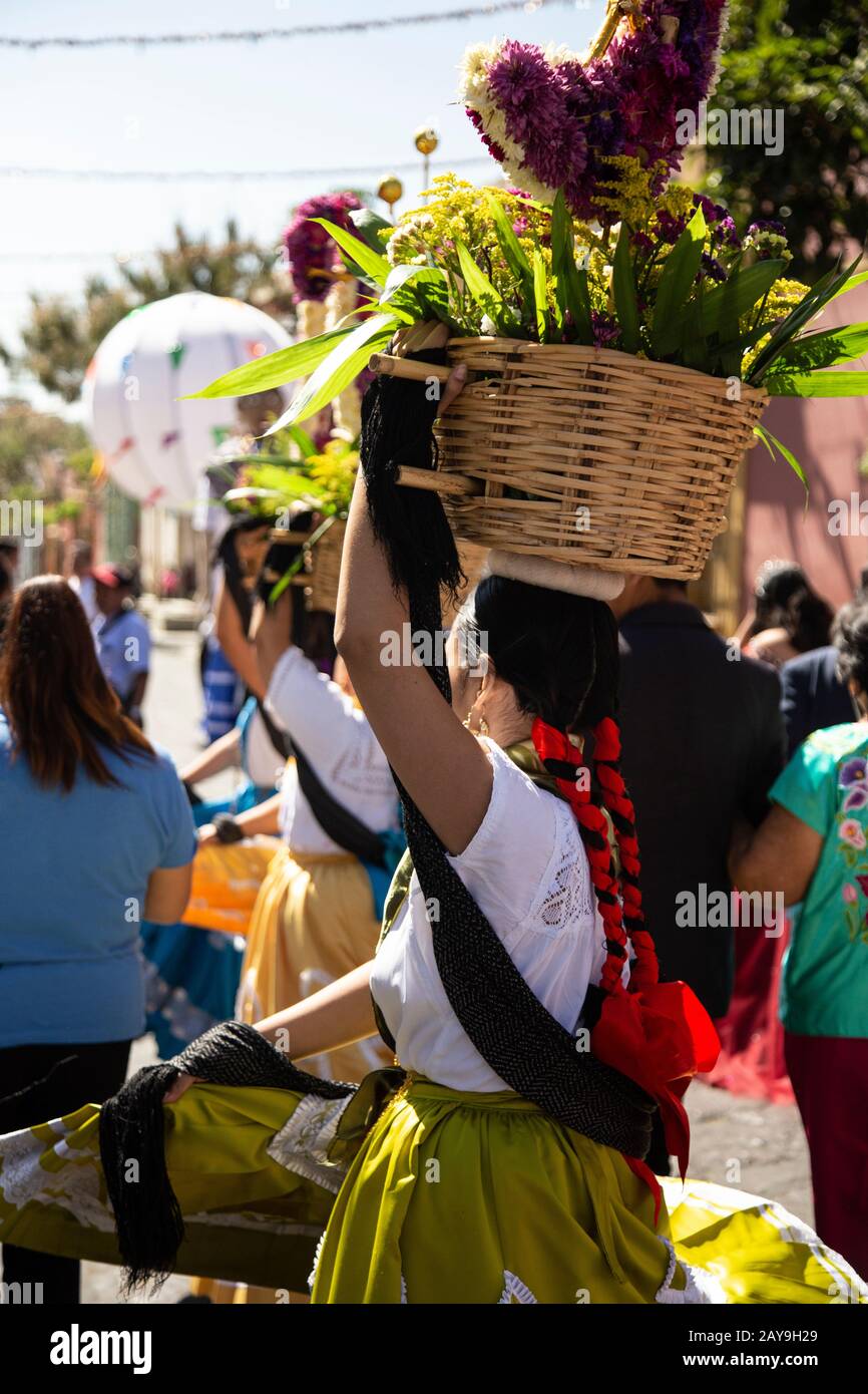 Mexican young women, wearing traditional costumes, carrying baskets Stock Photo