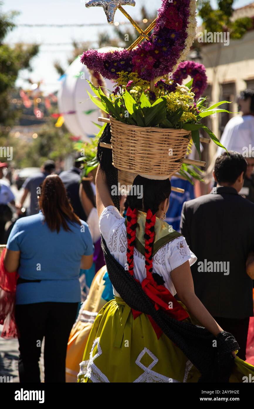 Mexican woman, wearing traditional costumes, carrying a flower baskets Stock Photo