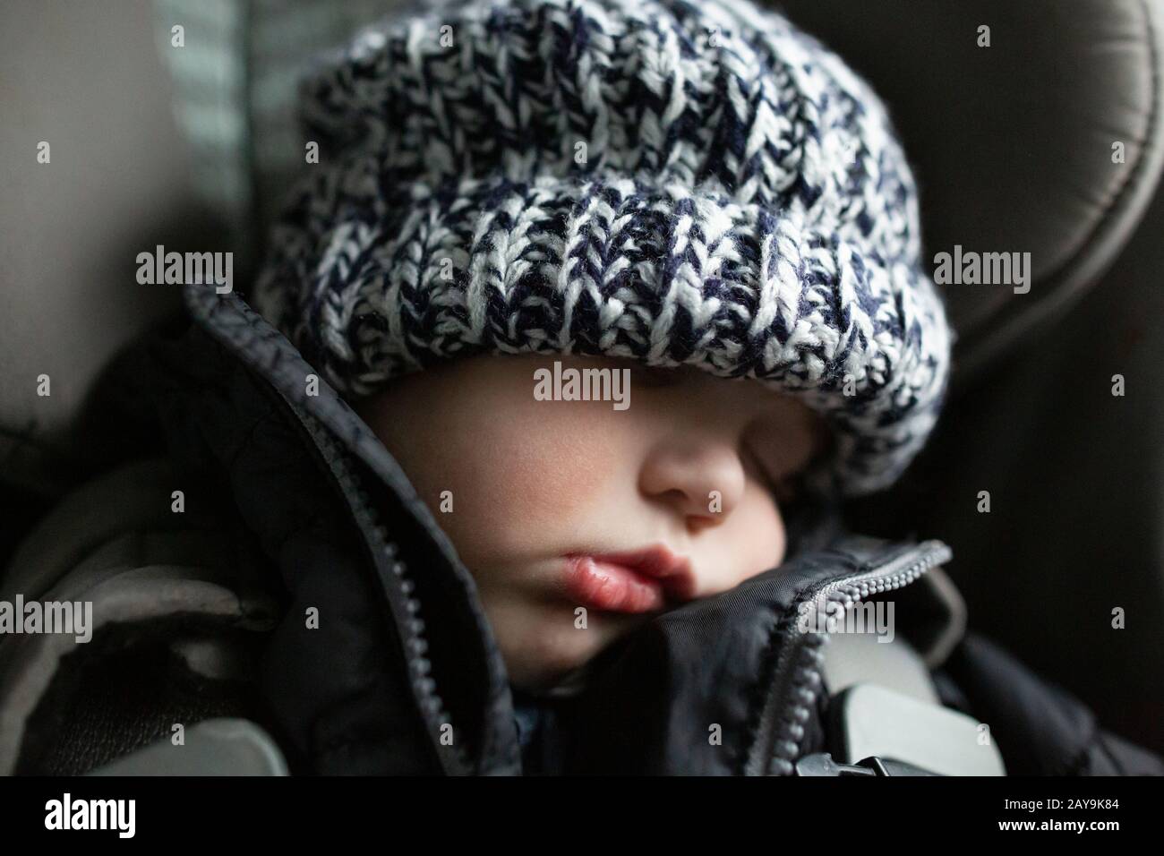 Close-up of toddler boy asleep in carseat while traveling in car Stock Photo