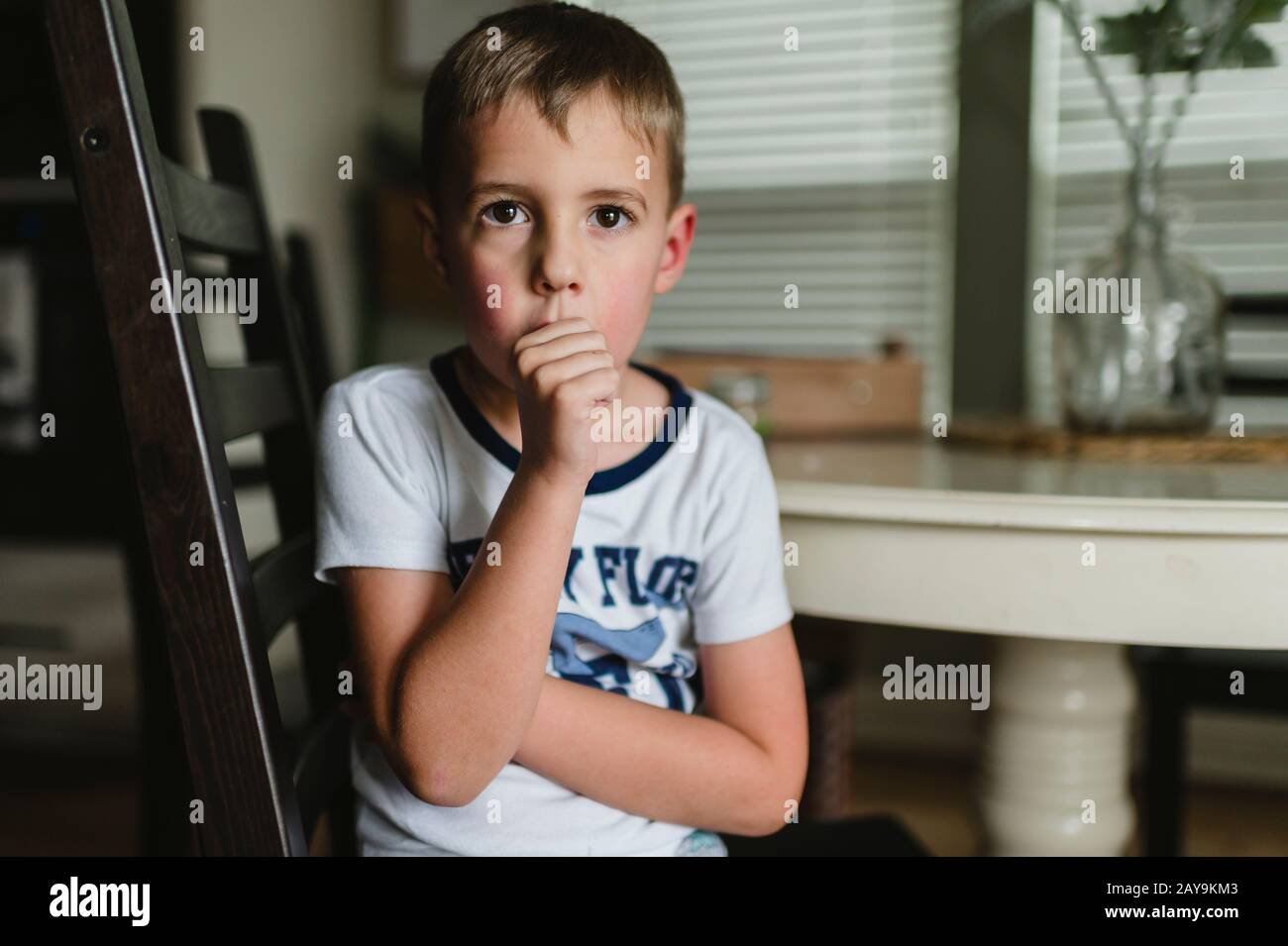 Young Boy Sucking Thumb at the Table in Pajamas in Buda Texas Stock Photo