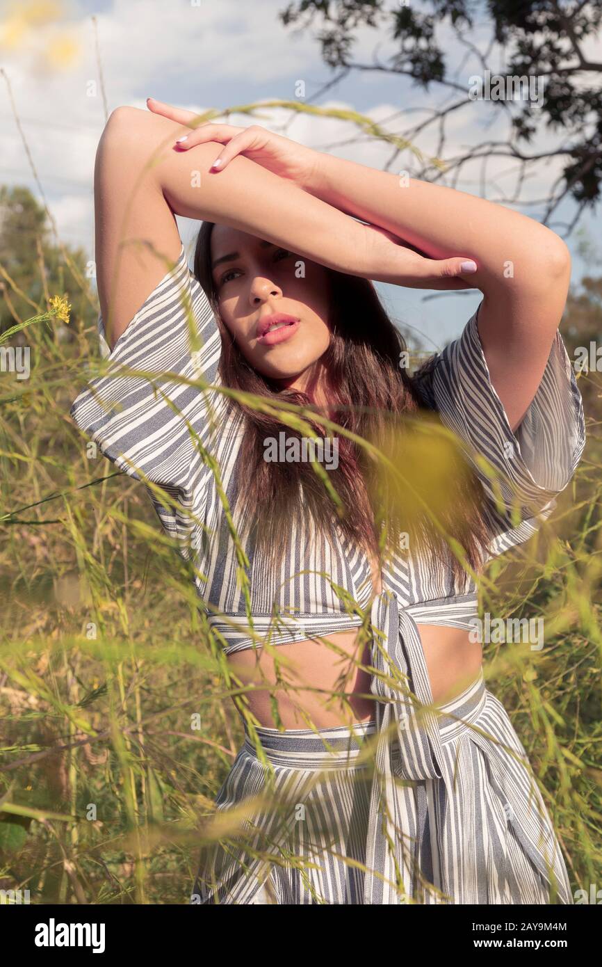Beautiful Latina woman in afternoon sun and flower fields Stock Photo