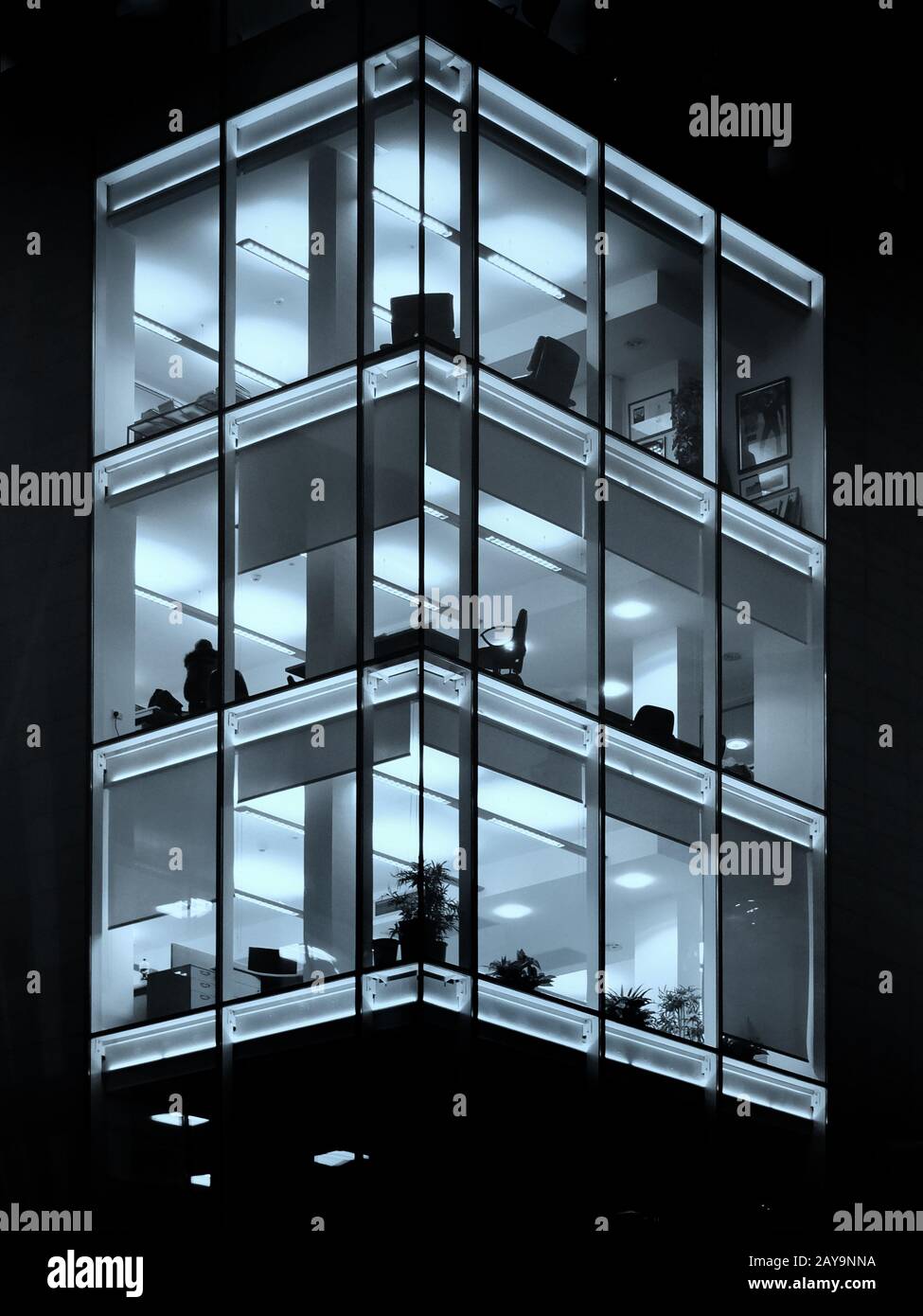 a stylish modern office building illuminated at night with blue geometric windows Stock Photo