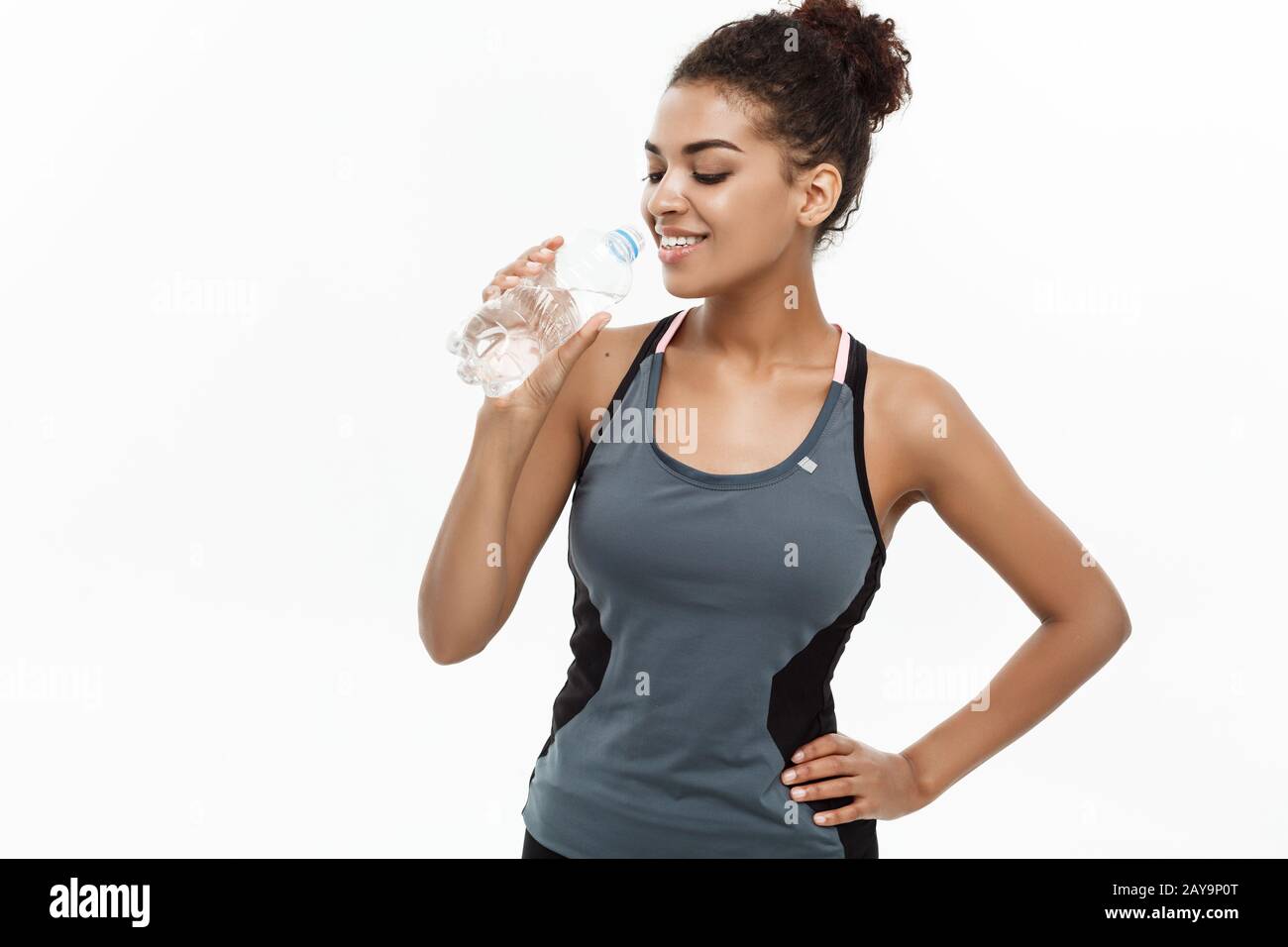 Healthy and Fitness concept - beautiful African American girl in sport  clothes drinking water by plastic bottle after workout. I Stock Photo -  Alamy