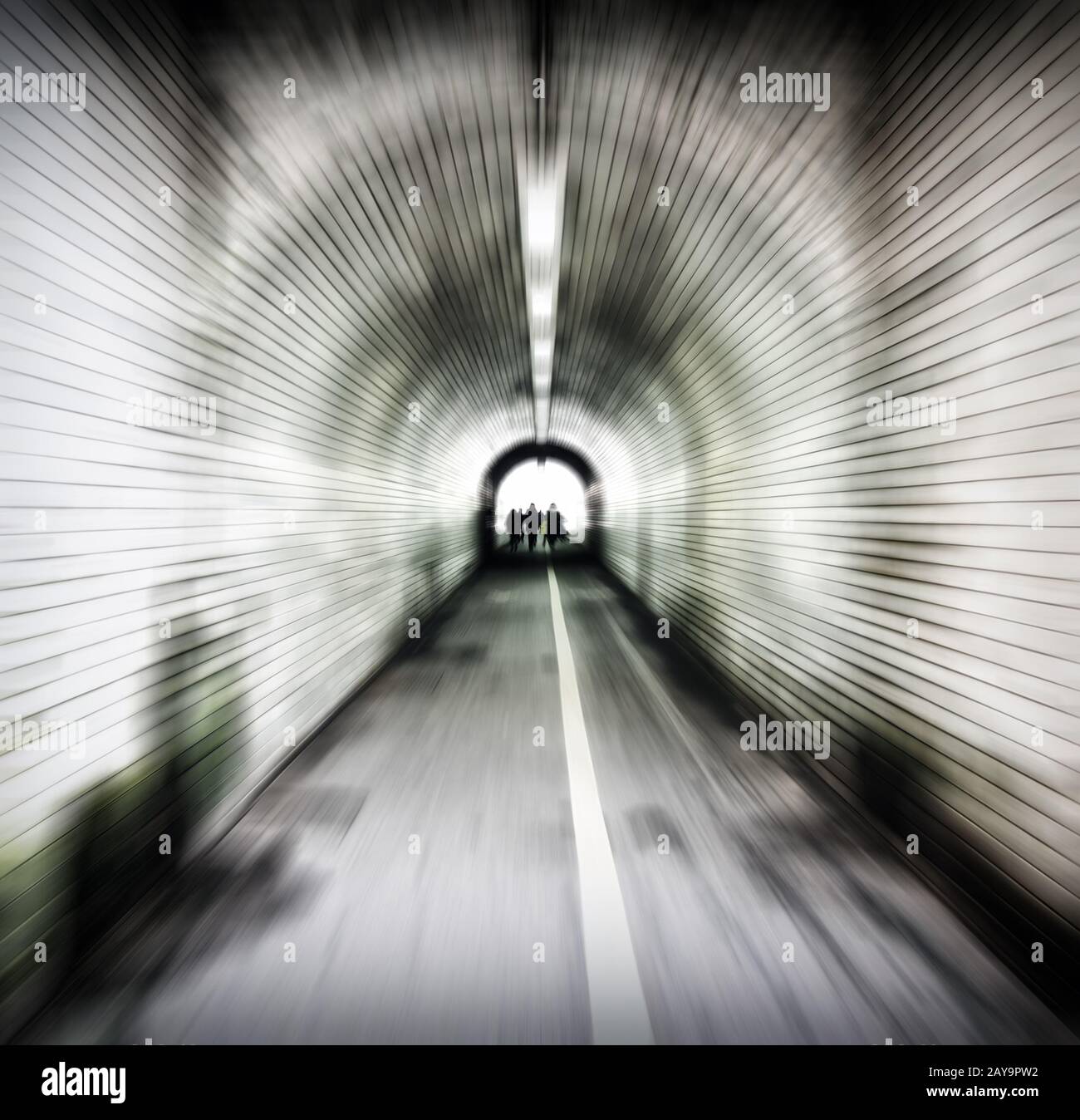 zoom blur image of an old dark pedestrian tunnel with unidentifiable people emerging into the light Stock Photo