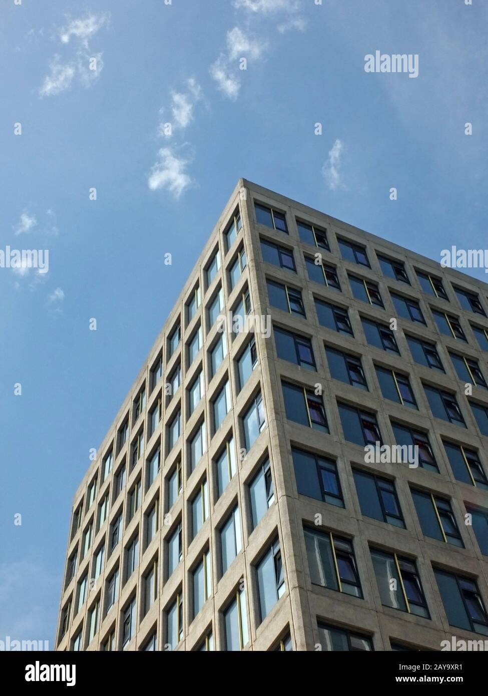 vertical angled corner view of a white high white concrete buildings with sunlit blue sunny sky Stock Photo