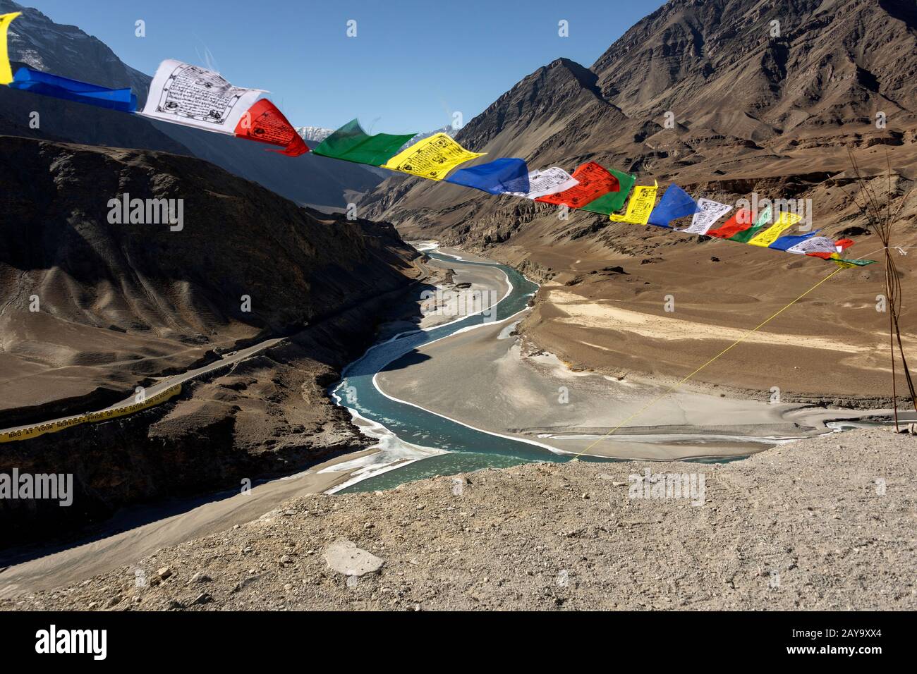 Prayer flags blowing in the wind above the confluence of the Indus and Zanskar rivers, Ladakh, India Stock Photo