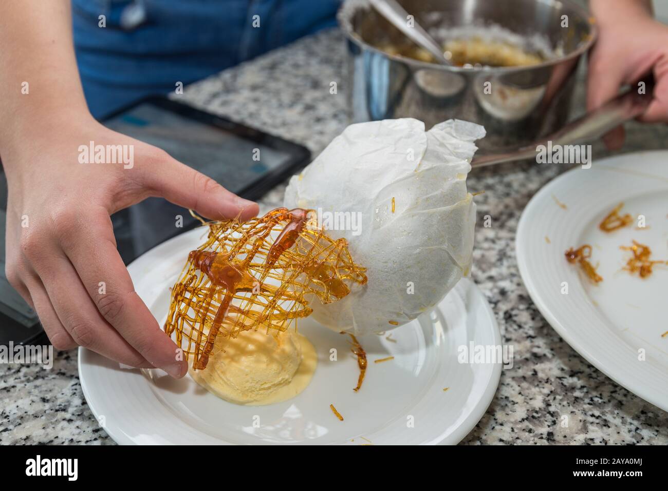 Preparation of caramelized sugar coating with vanilla ice cream via tablet instructions Stock Photo
