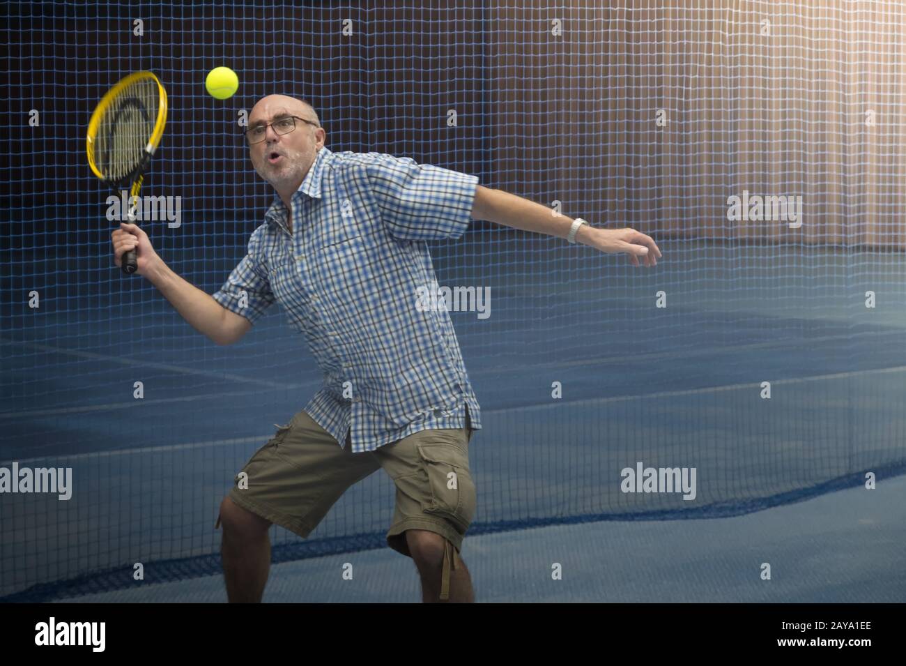 Senior plays tennis indoor. Stock Photo