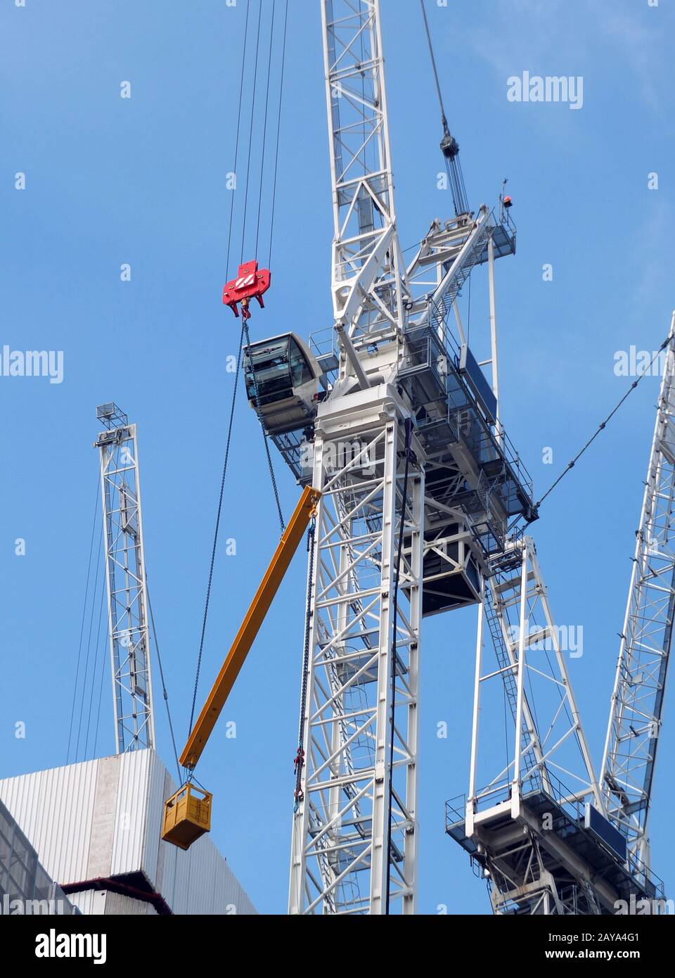 tall construction cranes working on a large development site with concrete large structure Stock Photo