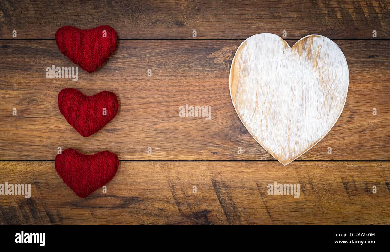 Large white wooden hart and three red cuddle hearts isolated on vintage