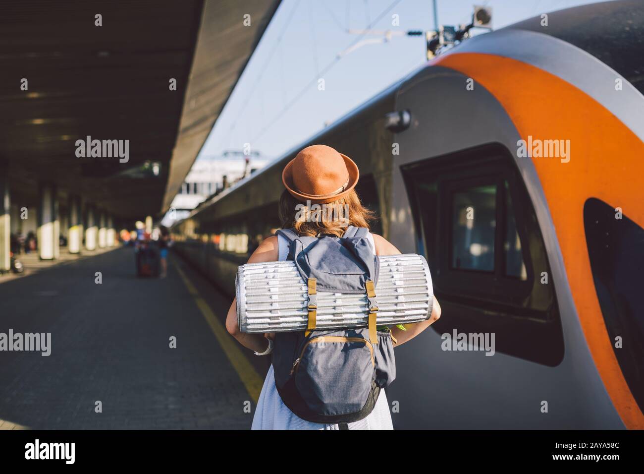 Theme transportation and travel. young caucasian woman standing at train station platform near train backs train background with Stock Photo