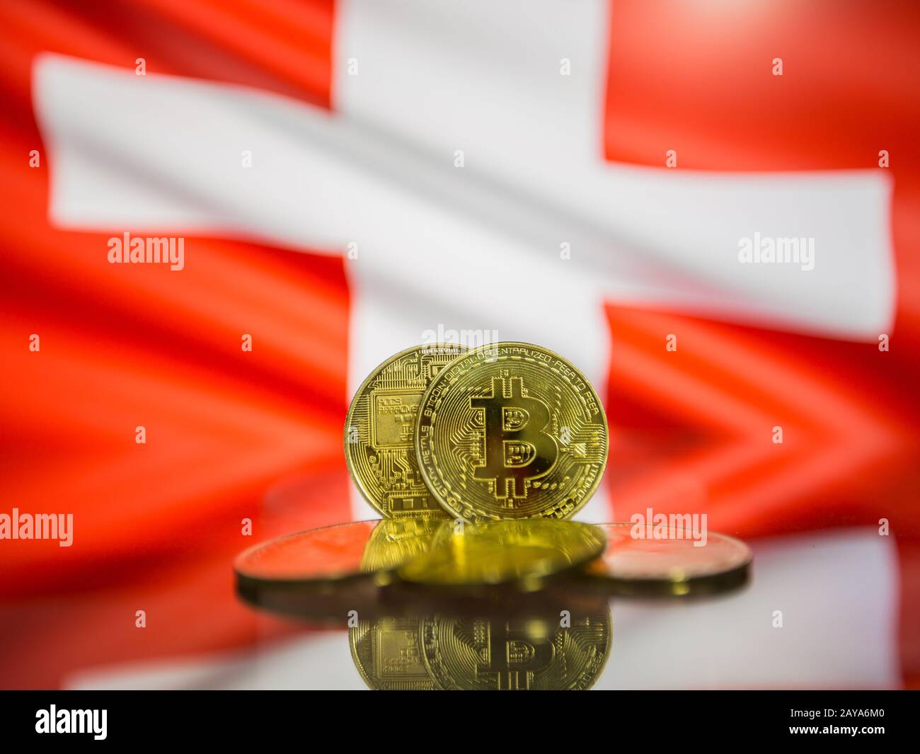 Bitcoin gold coin and defocused flag of Switzerland background. Virtual cryptocurrency concept. Stock Photo