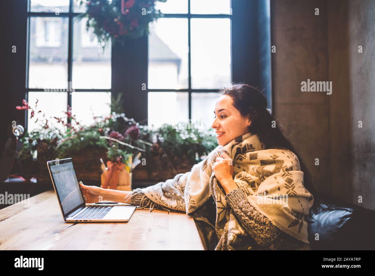 Woman is surprised when a hand holding a bouquet of flowers sticks out the  monitor of laptop she is using Stock Photo - Alamy