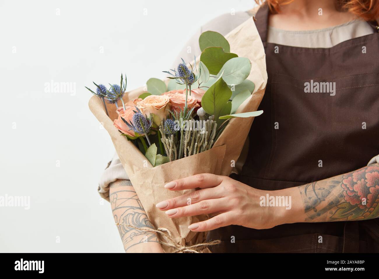 Fresh flowers living coral roses and eryngium as a congratulate bouquet in girl's hand with tattoo, copy space. Post card for Mo Stock Photo