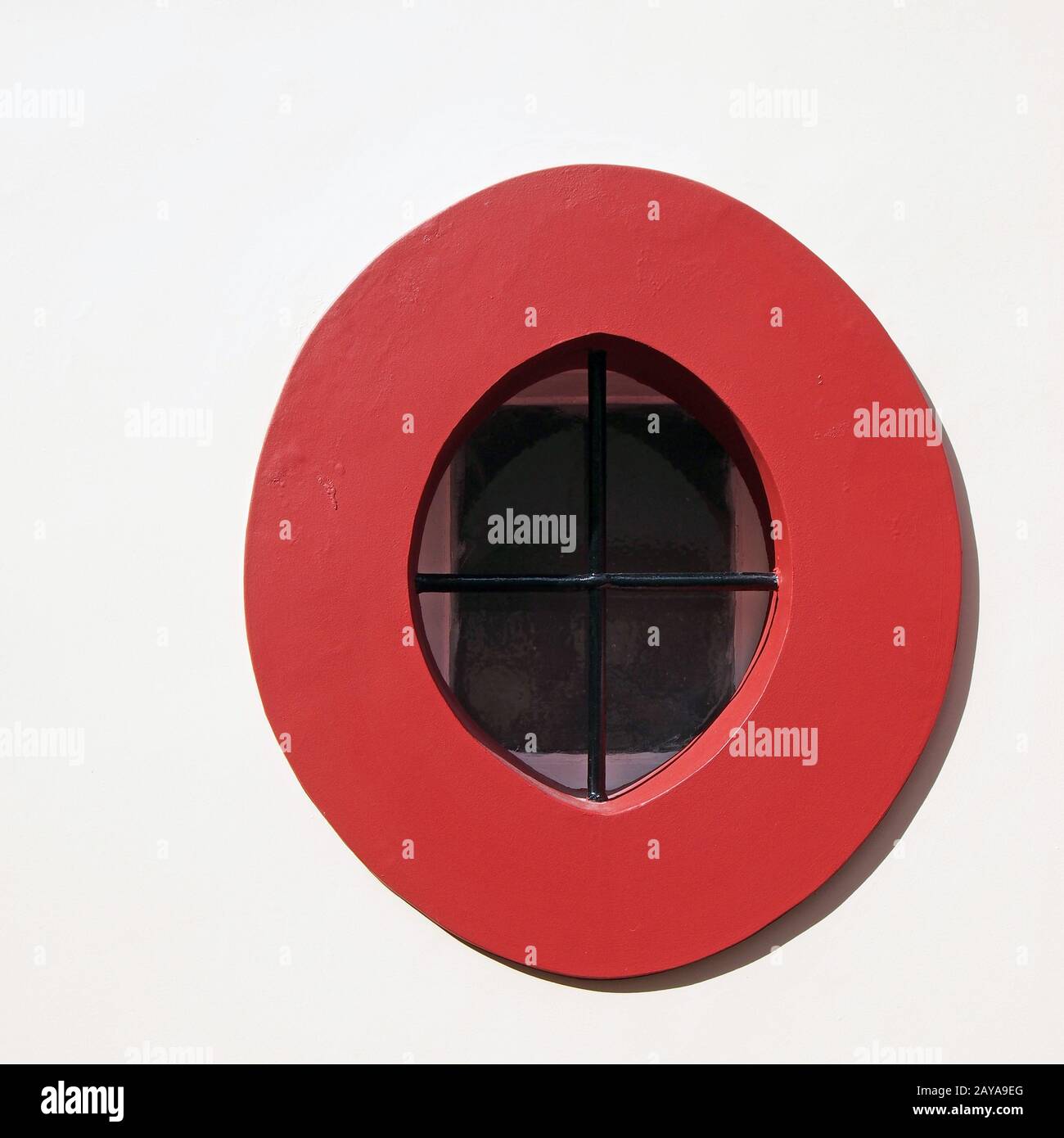 bright red stone oval window frame in a white wall with black metal ...