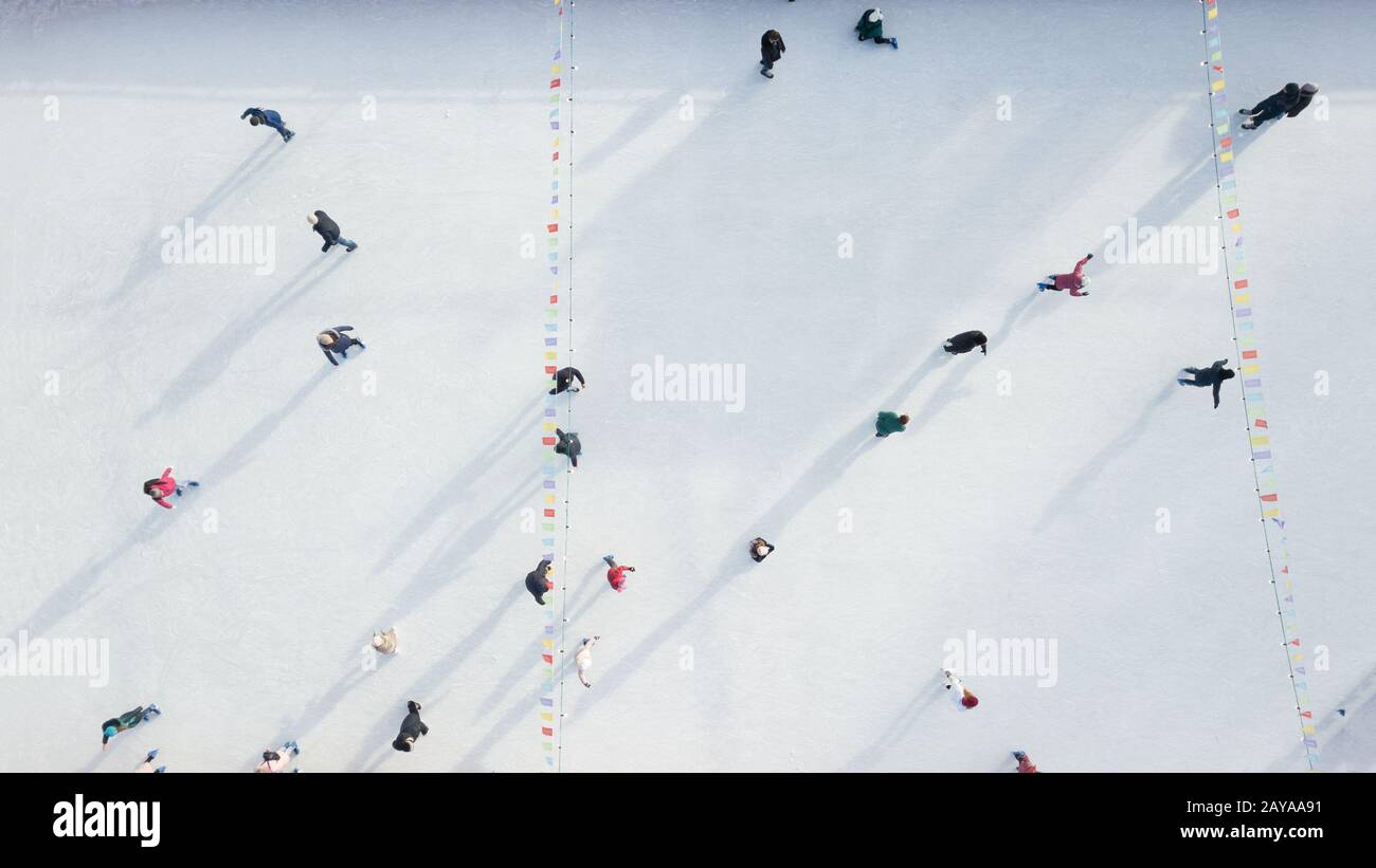 Aerial view of a drone on an open ice rink with people on a winter ...