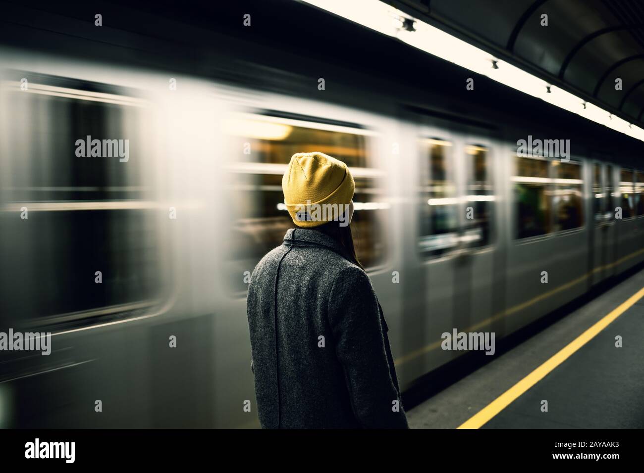Young woman waits at the metro station while the train arrrives. Transportation and travel concept. Stock Photo