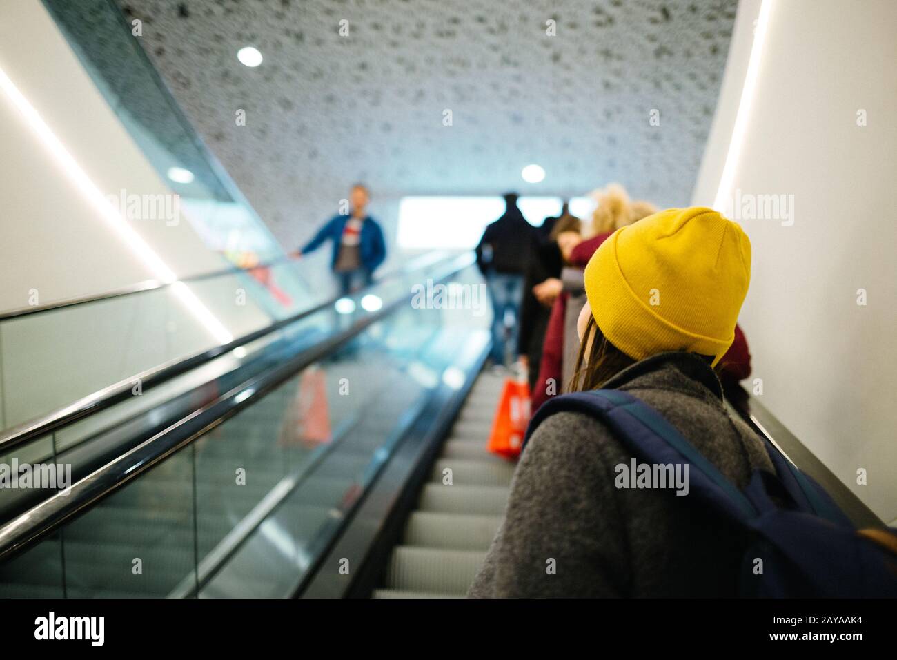 Young girl driving up at an escalator in a mall. Stock Photo