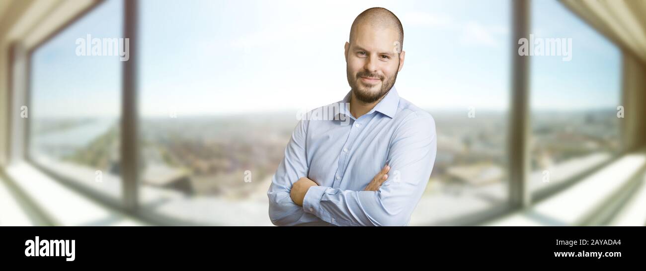 Successful smiling man standin in front of the window of a skyscrapper. Real estate Stock Photo