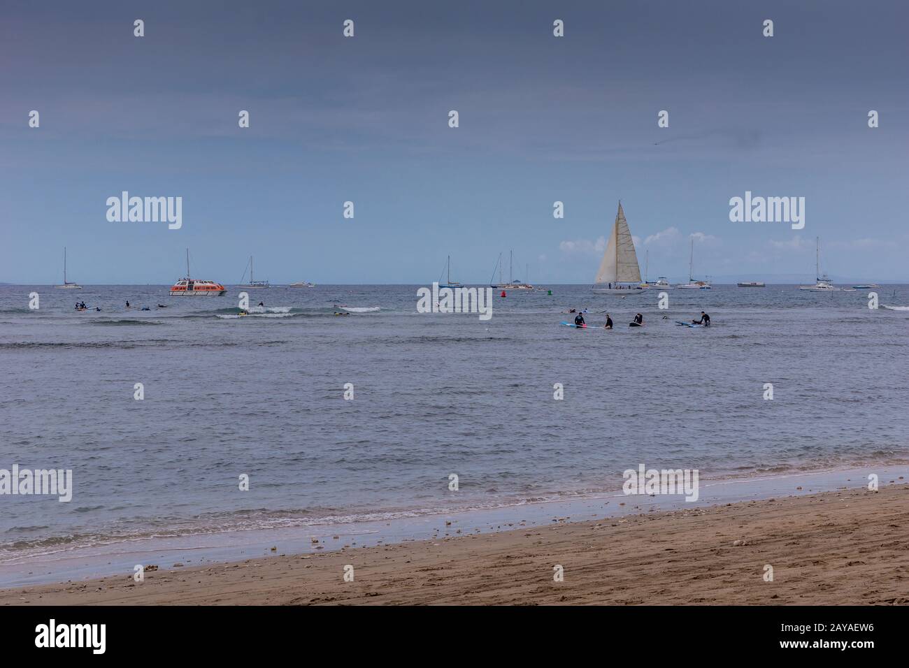 Lahaina, Maui, Hawaii, USA. - January 12 2012: Off sand beach, view over blueish ocean with surfers, swimmers and sail boats under blue sky. Stock Photo