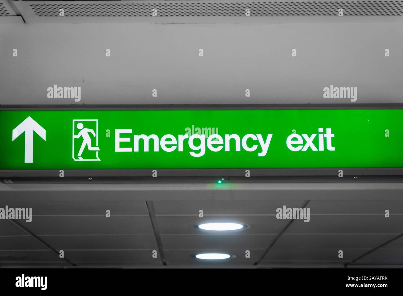 Emergency exit sign glowing green  in airport- for safety, fire drill, case of emergency Stock Photo