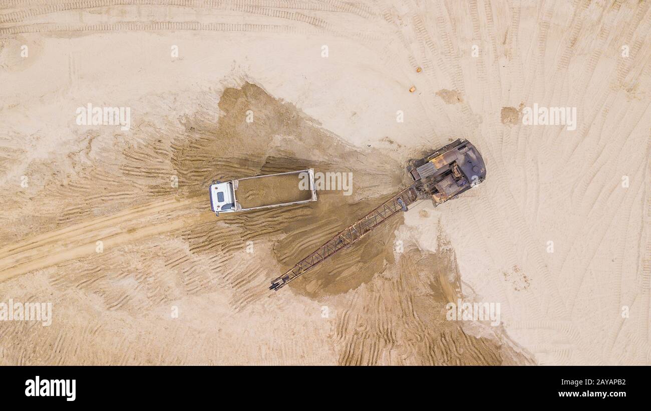 View from above of excavator pours sand into the truck. On the construction site. Stock Photo