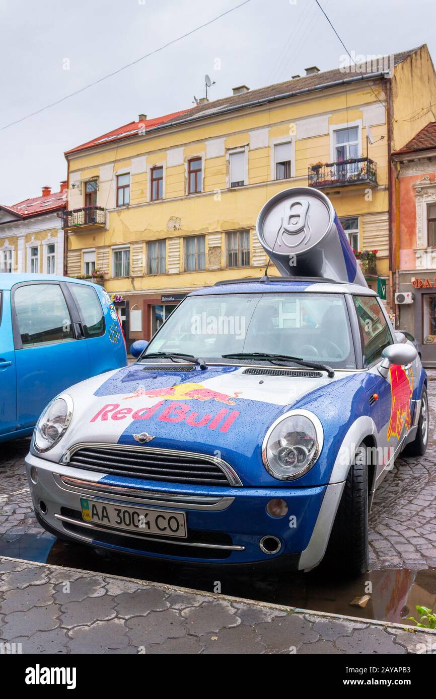 Uzhhorod, ukraine - 14 JUL, 2013: Red Bull mini cooper publicity car with a can of energy drink behind. fancy car tuning used for promotion. wet adver Stock Photo